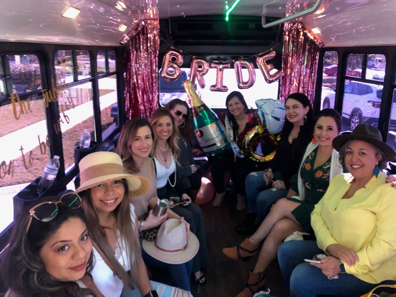 A bachelorette group in sun hats on board, with a BRIDE balloon banner behind them
