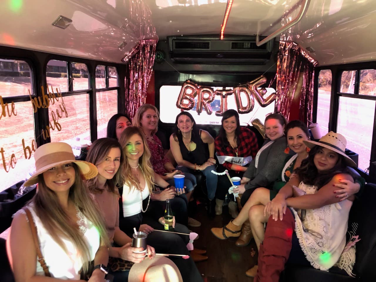 A bachelorette group laughing under a BRIDE balloon banner